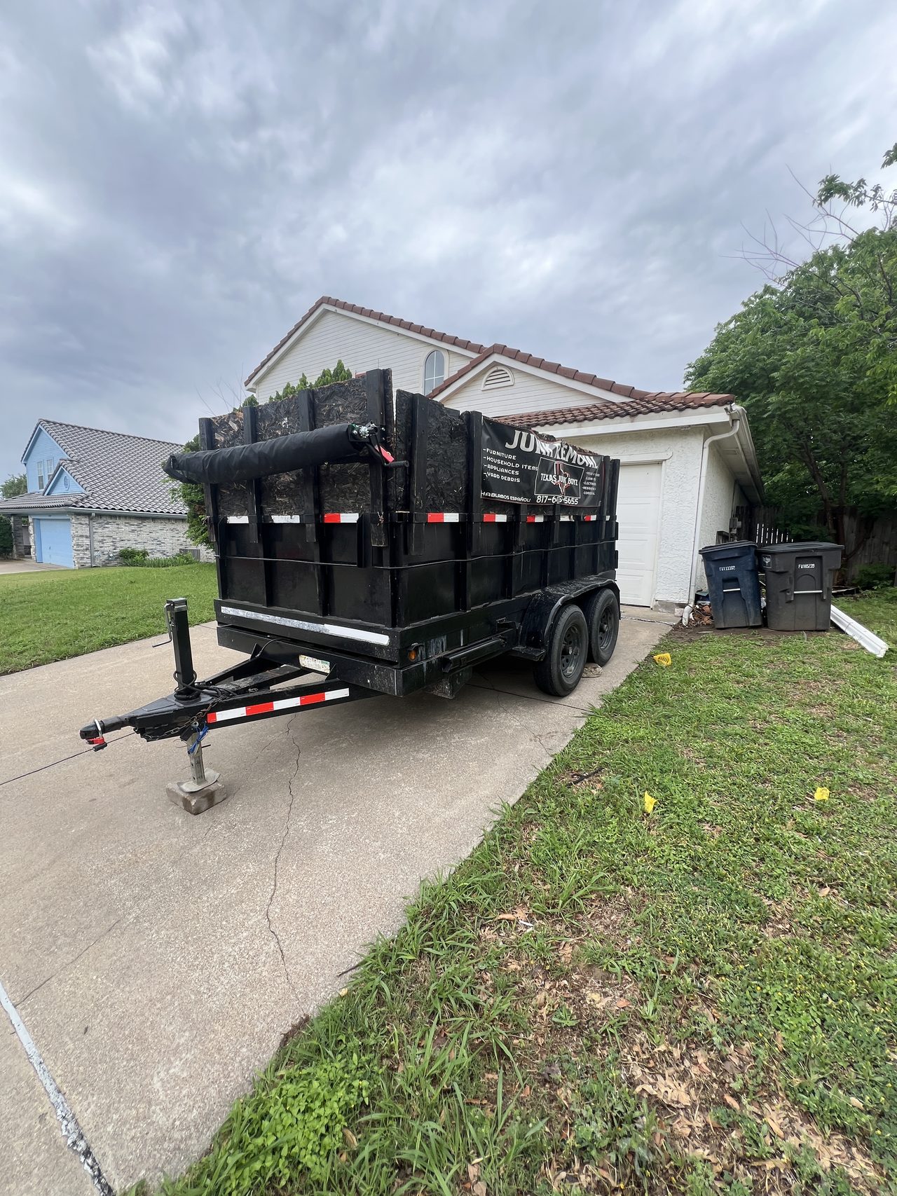 Texas Junk Boyz dump trailer parked in a residential driveway ready for a hot tub removal job